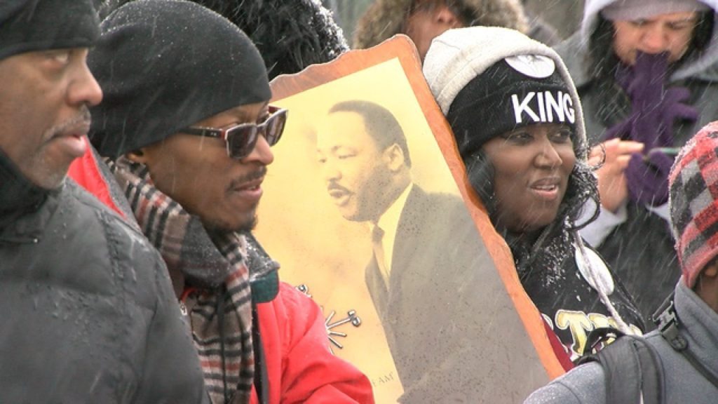 People holding up a picture of Dr. Martin Luther King Jr. as they attend the Marade