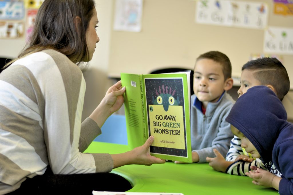 A woman reading a book to three children